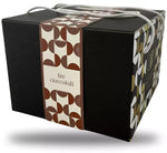 Un'elegante scatola regalo custodisce un Panettone artigianale ai Tre Cioccolati, vero trionfo di autentici sapori italiani gourmet.