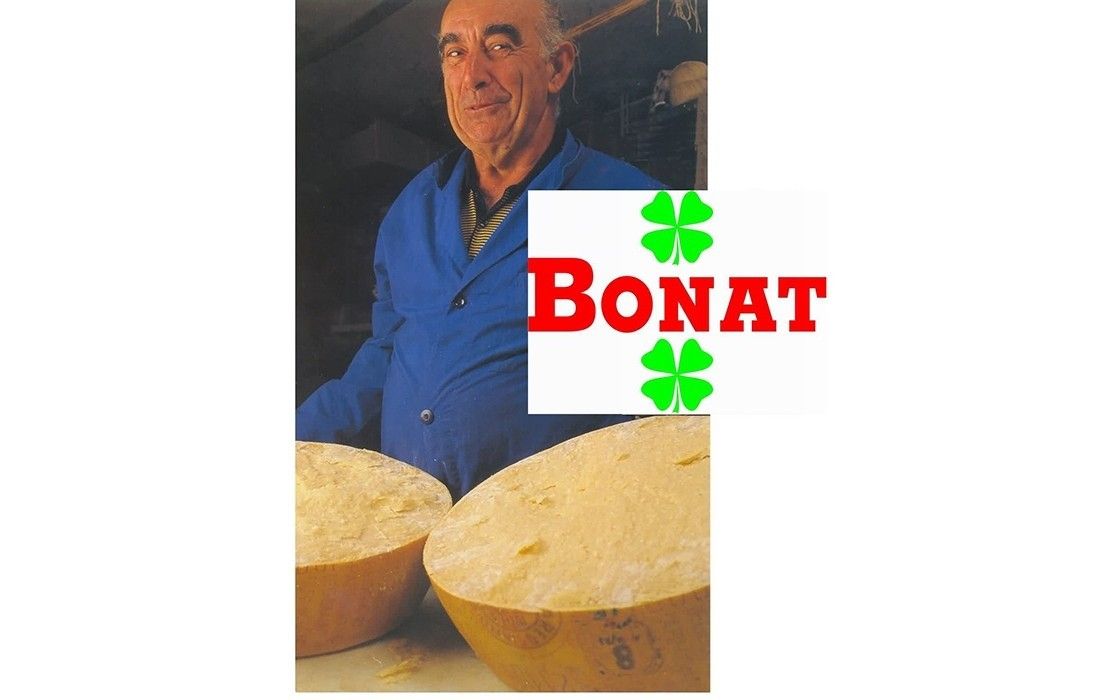 Un anziano casaro mostra con orgoglio le sue forme di Parmigiano Reggiano Bonat, stagionate per più di 22 anni, un emblema della qualità e tradizione italiana DOP.