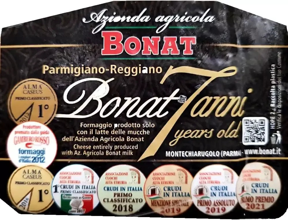 Un formaggio DOP Parmigiano Reggiano Bonat, stagionato per 7 anni, presentato in una confezione raffinata e decorata con medaglie di eccellenza.