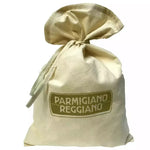 Elegante sacchetto di tessuto racchiude un Parmigiano Reggiano DOP stagionato 7 anni di Bonat, emblema del sapore italiano autentico.