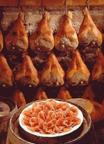 Un trancio di Prosciutto di Parma DOP, stagionato per 16 mesi in una cantina tradizionale, presentato su un piatto, pronto per deliziare i sensi con il suo aroma inconfondibile.