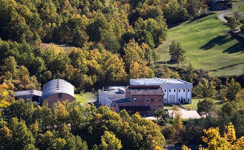 Splendida vista dall'alto di un caseificio isolato a Borgotaro, avvolto tra boschi autunnali, luogo di origine del Parmigiano Reggiano DOP.