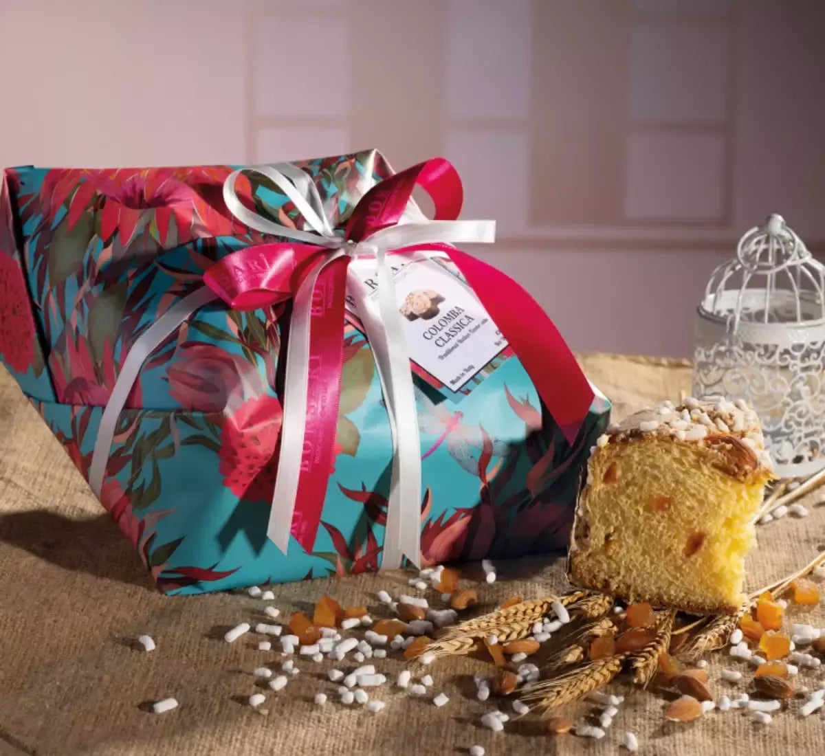 Una colomba classica artigianale, decorata con arancia candita e glassa alle mandorle, presentata in un'elegante confezione floreale.