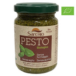 Un barattolo di pesto biologico Sarchio, privo di aglio, formaggio e glutine, adornato con un'etichetta e una foglia decorativa.