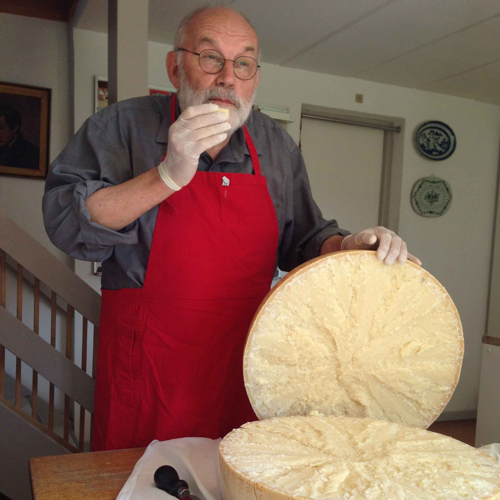 Maestro caseario Karsten assaggia forma di formaggio artigianale, rivelando sfumature di sapore in un'accogliente cucina danese.