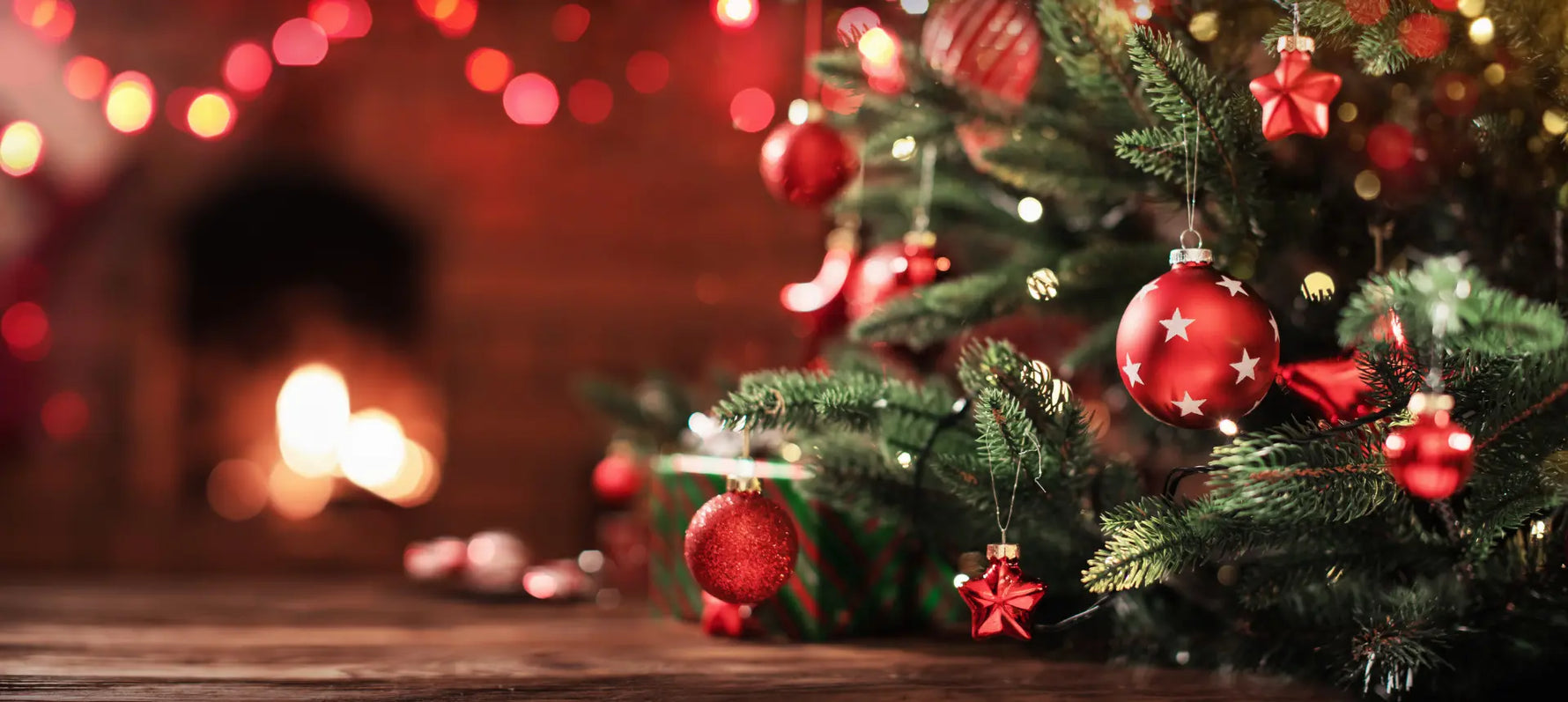 Christmas tree decorated with red ornaments and a backdrop of warm lights, evoking a cosy festive atmosphere.